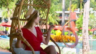 Romantik kadın yazın tropikal lüks oteldeki bambu salıncakta dinleniyor.