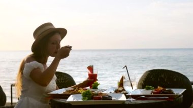 Tatil tatilindeki genç kadın meyveli karpuz kokteylleriyle yemeğinin tadını çıkar.