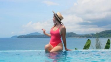 Yüzme havuzunda oturan mayo giymiş seksi genç bayanın açık havada tatili.