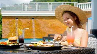 Yazın açık hava otel restoranında öğle veya kahvaltı yapan bir kadın.