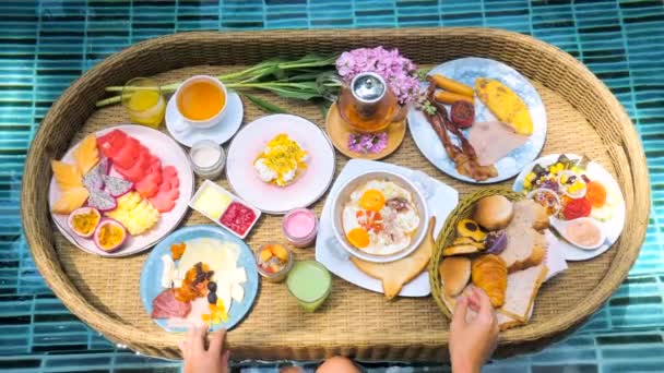 Pasti colorati per colazione o pranzo con mani di donna su vassoio galleggiante in piscina — Video Stock