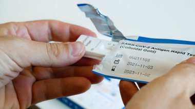 İnsan steril paketi kendi teşhisi için koronavirüs antijen testiyle açar.