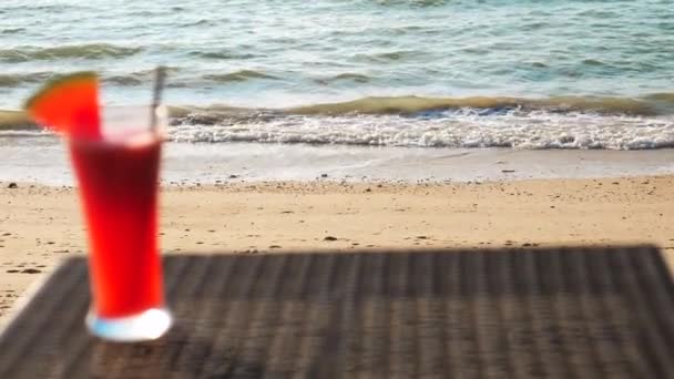 Απεσταλμένος χυμός καρπουζιού στο τραπέζι στην τροπική καλοκαιρινή παραλία σε συννεφιασμένη ημέρα — Αρχείο Βίντεο