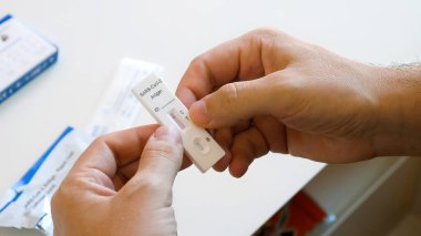 Yüzü maskeli bir adam, test sonucu negatif çıktı. Covid-19 kendini test ediyor.