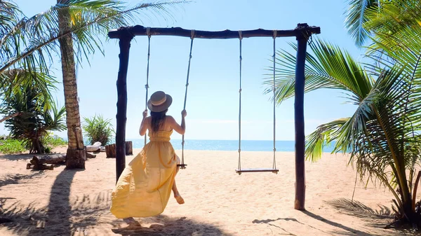 Wolny ruch kobiety podróżującej na drewnianej huśtawce na tropikalnej, piaszczystej plaży, błękitne morze — Zdjęcie stockowe