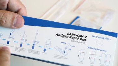 Adam elinde hızlı bir test ile bir kutu tutuyor ve talimatları okuyor.