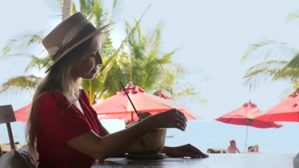 Jonge reisvrouw op tropische zomervakantie in café, verse kokosnoot drinkend — Stockvideo