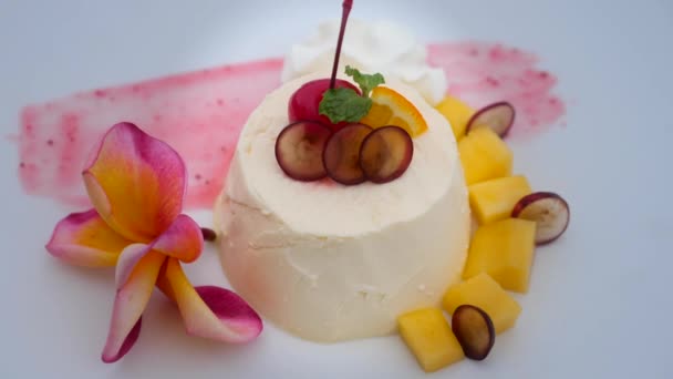 レストランでfrangipani花とホワイトプレートのパナコッタデザートマンゴー — ストック動画