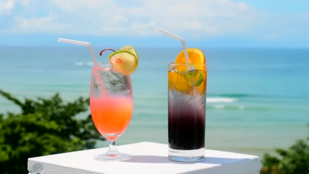 Dos cócteles tropicales de hielo fresco en la mesa del bar con la playa de mar en el fondo — Vídeo de stock