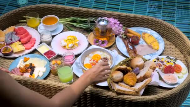 Woman hand take bun of bread basket, breakfast or lunch floating tray in pool — Video Stock