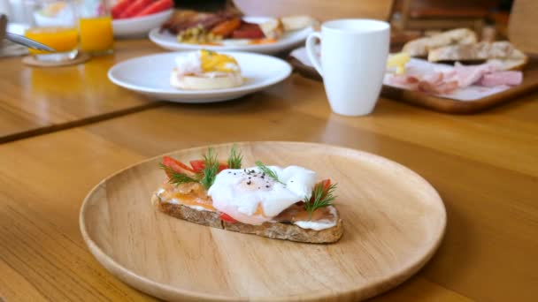 Manos masculinas con tenedor y cuchillo cortado benedicto huevo con yema líquida en tostadas — Vídeos de Stock