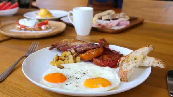 美式早餐，有阳光明媚的一面煎鸡蛋，咸肉，西红柿，面包烤 — 图库视频影像