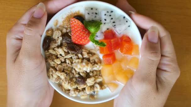 Woman hands rotate bowl of homemade granola with yogurt, raisins, fresh berries — Stockvideo