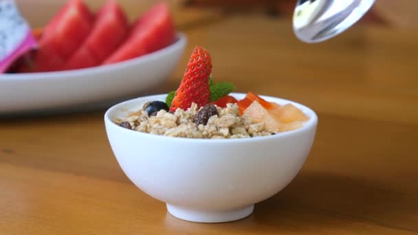 Human hand with spoon eat healthy breakfast food, bowl of granola with yogurt — Stock Video
