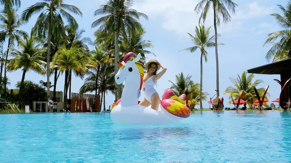 Podekscytowana młoda kobieta tańczy i bawi się na pływającym jednorożcu w basenie — Zdjęcie stockowe