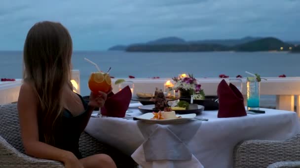 Romantic dinner with candles, sexy woman in elegant evening dress hold cocktail