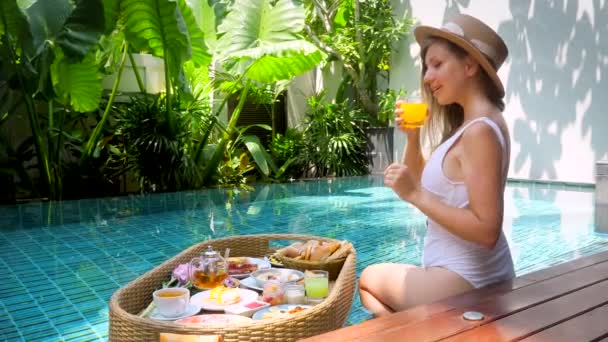 Jeune femme se détendre près de la piscine et boit du jus d'orange, dame sexy en plein air — Video