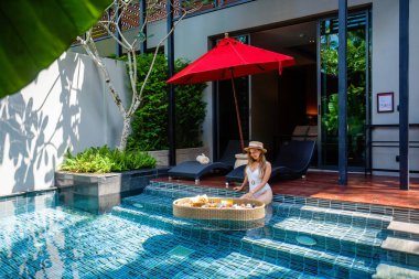 Mayolu kız havuzda havuz tepsisinde dinleniyor ve yüzen kahvaltı yapıyor.