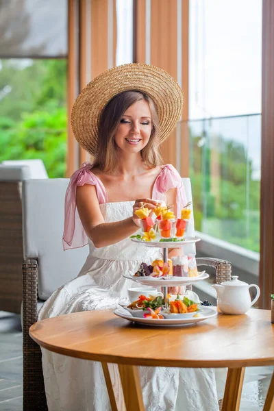Délutáni tea egy luxus étteremben kilátással a tengerre. Elegáns nő eszik gyümölcsöt — Stock Fotó