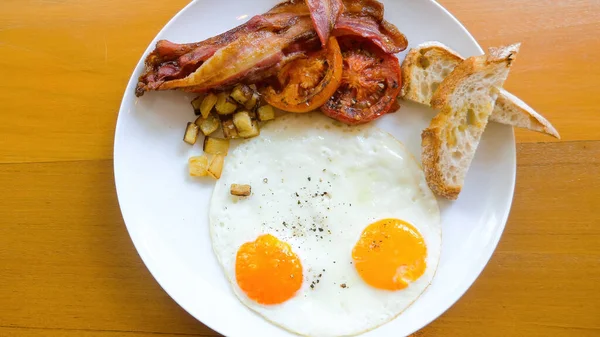 Café da manhã americano com ovos fritos laterais ensolarados em mesa de madeira no restaurante — Fotografia de Stock