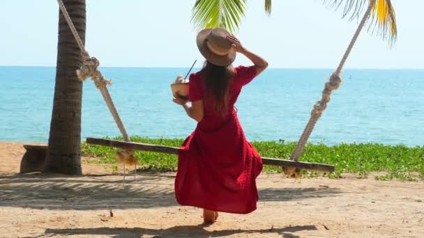 Junge Frau auf Schaukel am Sandstrand an heißen, sonnigen Sommertagen, Reisen in den Urlaub — Stockvideo