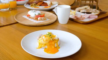 Cut egg benedict with liquid yolk, english muffin in restaurant, breakfast food