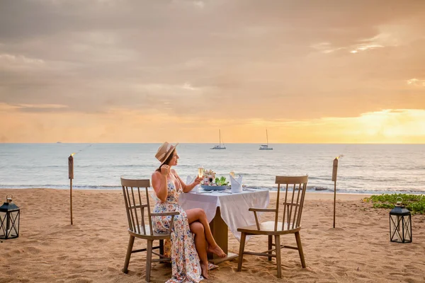 Vrouw zit alleen op tafel met lantaarn voor een romantische maaltijd op het strand — Stockfoto