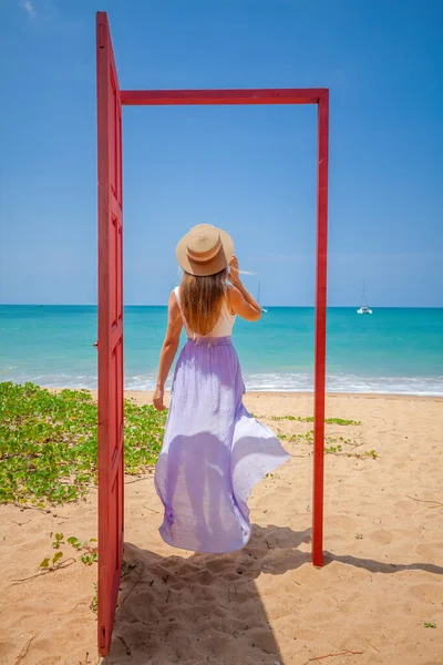 Tropische reisvakantie. Reiziger vrouw in rode deur op het strand naar turquoise zee — Stockfoto