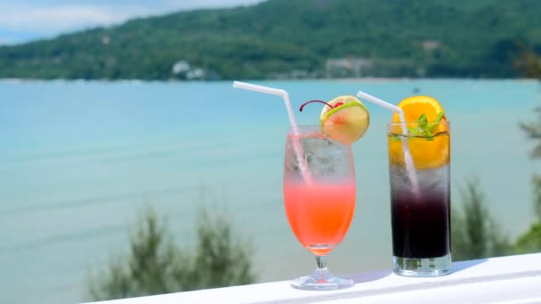 Два коктейльных бокала с фруктовыми украшениями в роскошном отеле с видом на море — стоковое видео
