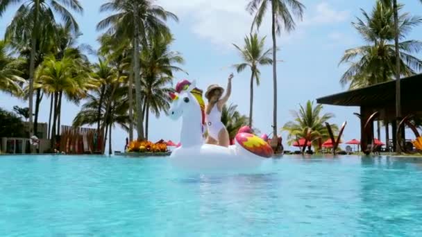 Женщина на надувной игрушки весело в бассейне на роскошном курорте отеля с пальмами — стоковое видео