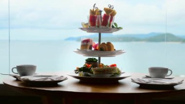 High tea set with assortment of sweets, cakes, sandwiches, fruit canape on table
