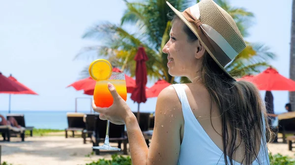 Aantrekkelijke jonge toeristische vrouw die verfrissende cocktail drinkt bij het zwembad, geniet van zee, palmbomen en uitzicht op het strand. Gelukkig lachend meisje relaxen in resort met niet-alcoholische drank. Phuket, Thailand. — Stockfoto