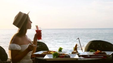 Kadın turist deniz manzarasına bakar, tatilin tadını çıkarır, otelde akşam yemeği yer.