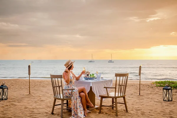 Vrouw zit alleen op tafel met lantaarn voor een romantische maaltijd op het strand — Stockfoto