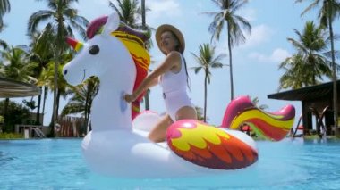 Mayo giymiş bir kadın tropik tatil köyünde mavi yüzme havuzunda oynuyor.