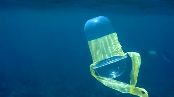 Plastik bardakla kristal mavi suda güneş ışınlarında yüzen plastik bir bardağın sualtı videosu. Çevresel plastik kirliliği sorunları kavramı. Dünya okyanus günü. Okyanustaki çöp.. — Stok video