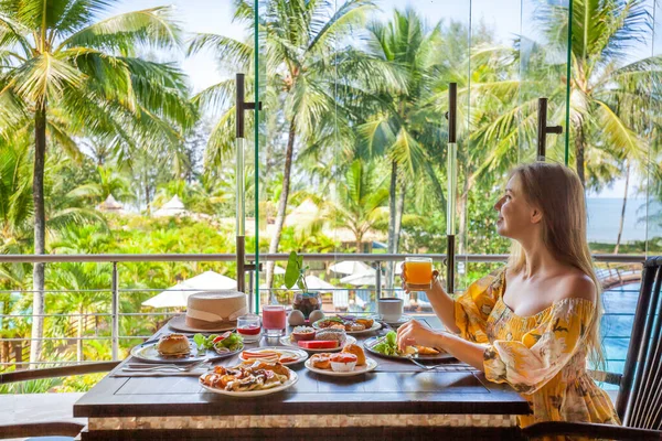 Tropik tatil. Arka planda deniz ve palmiye ağaçları olan modern otel otelinde kahvaltı. Tayland, Phuket 'te yaz tatilindeki gezgin kadın. Güneydoğu Asya 'da egzotik seyahat