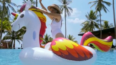 Mutlu kadın yüzme havuzunda şişme yüzme tüpüyle eğleniyor, yaz gününün tadını çıkarıyor, güneşleniyor ve modern tropikal tatil beldesinde dinleniyor. Tatiller, yaz tatili ve tatil kavramını kutlamak..