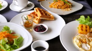Otelde ya da tatil köyünde kahvaltı. Tayland mutfağı. Restorandaki ya da kafedeki yemek masasının yakın görüntüsü. Kahve fincanı, portakal suyu, krep, waffle, salata, salata. Öğle, şube veya akşam yemeği konsepti.