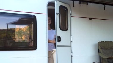 Kamp minibüsüyle yolculuk. Karavanla seyahat eden mutlu bir kadın. Kamp arabasından çıkan kadın gezgin doğa manzarasının tadını çıkarıyor. Karavan seyahati. Tatil kavramı