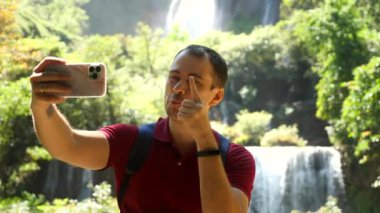 Mutlu sosyal medya içerikli yapıcı. Gülümseyen etkili konuşmalar videoda, dışarıda cep telefonuyla blog çekimleri. Yetişkin adam blogcu, video blogcusu akıllı telefonuyla özçekim filmi kaydediyor. Kameraya bakın..