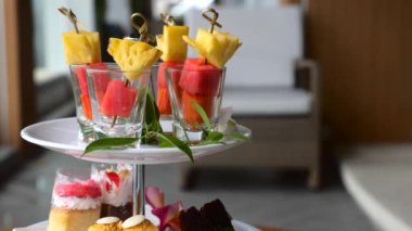 Beyaz tabakta renkli tropik karışık meyve şişleri. Bambu çubuklarıyla taze yaz meyveleri. Ananas, karpuz ve papaya ahşap kebap, aperatif, kek, kurabiye ikindi çayı..
