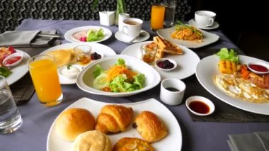 Öğle, şube veya akşam yemeği konsepti. Restorandaki ya da kafedeki yemek masasının yakın görüntüsü. Otelde ya da tatil köyünde kahvaltı. Tayland mutfağı. Kahve fincanı, portakal suyu, krep, waffle, salata, soğuk et.