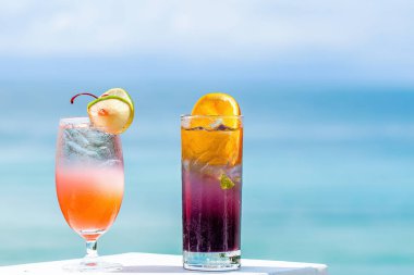 Yaz güneşli bir günde lüks egzotik tatil beldesinde kokteyller. Seyahat, tatiller, tatiller, turizm konsepti. Turkuaz deniz bulanık arkaplan. Tropikal lüks oteldeki meyveli mocktail buzlu içecekler. Yakın plan..