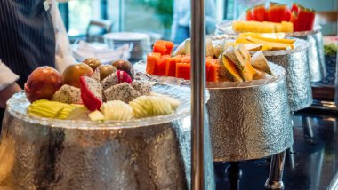 Modern otelde kahvaltı büfesi. Lüks otelde çeşitli taze tropikal meyveler. Lokantada renkli meyve tabağıyla birlikte yemek masası. Yaz tatili kavramı