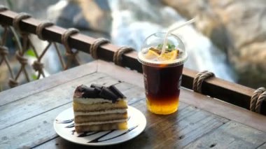 Erkek eli soğuk portakallı kahve ile plastik bardağı alır. Buzlu kahve, doğa geçmişi olan bir kafeye gidecek. Adam bir fincan organik kahve alıyor.