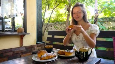 Kadın taze bir çöreği ısırıyor, açık kafedeki tadını ve kokusunu seviyor, tabaklar dolusu taze hamur işiyle masada oturuyor. Tatlı ve sağlıksız yiyeceklere bağımlı..