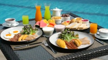 Tropikal bir villada yüzme havuzlu renkli lezzetli bir kahvaltı. Bir masa dolusu egzotik meyve, yumurta, sosis ve pastırma. Modern tatil beldesinde tatil. Yaz tatili