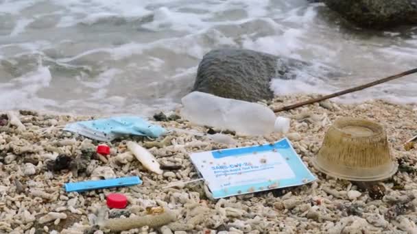 コビトテスト プラスチックボトルや他のゴミと再利用可能なフェイスマスクは ビーチにあります コロナウイルスCovid 19は汚染に貢献しています 海洋汚染の概念 — ストック動画