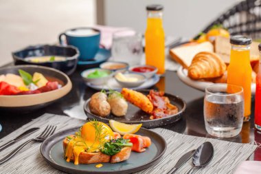 Lüks otelde nefis bir kahvaltı. Tabaklar dolusu taze yemek, taze sıkılmış meyve suyu, yumurta, meyve ve sosis. Modern tatil köyünün önünde sabah büfesi..